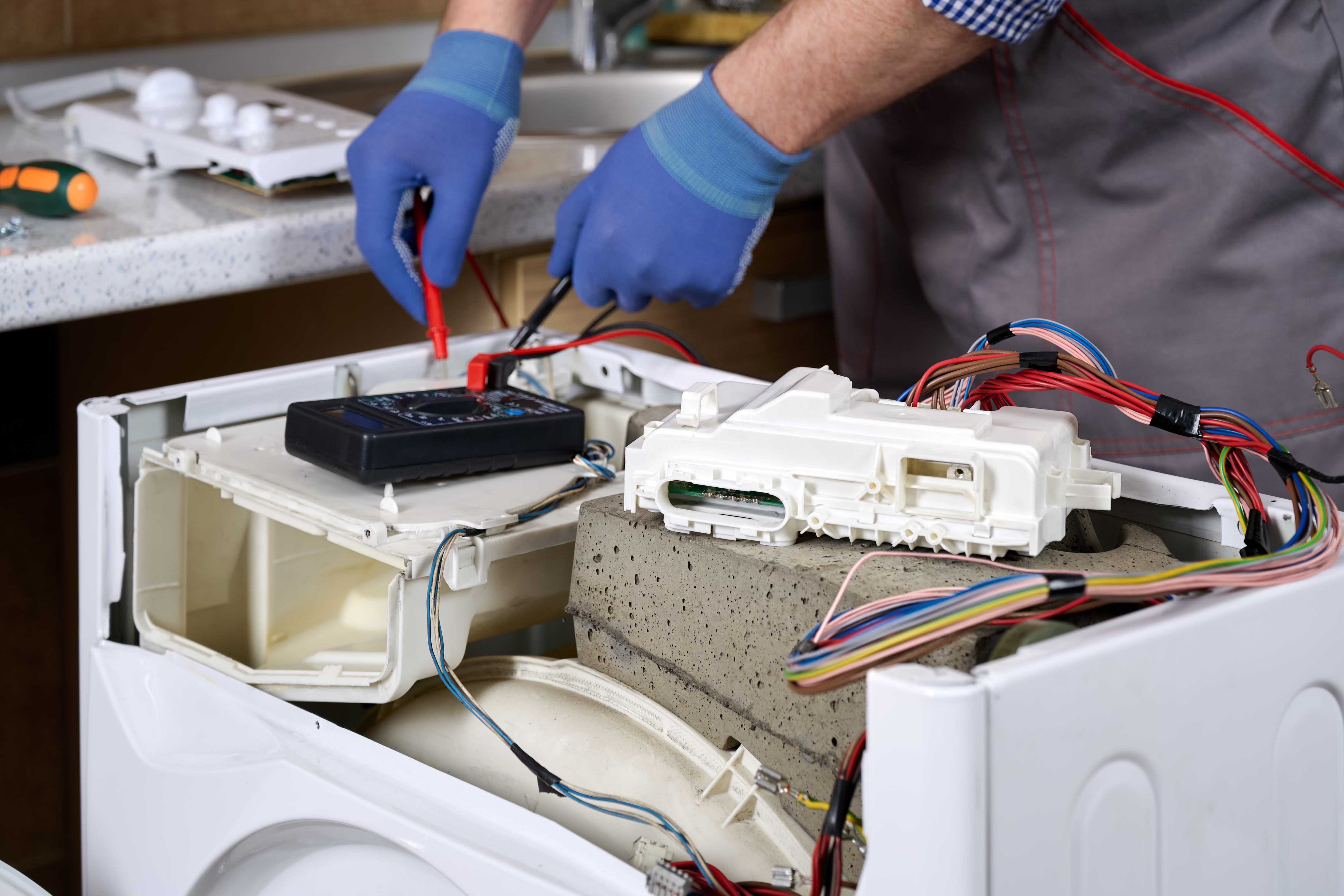 Close-up of a damaged washing machine control module. A service engineer checks the integrity of electrical circuits and the functionality of individual components. Selective focus.